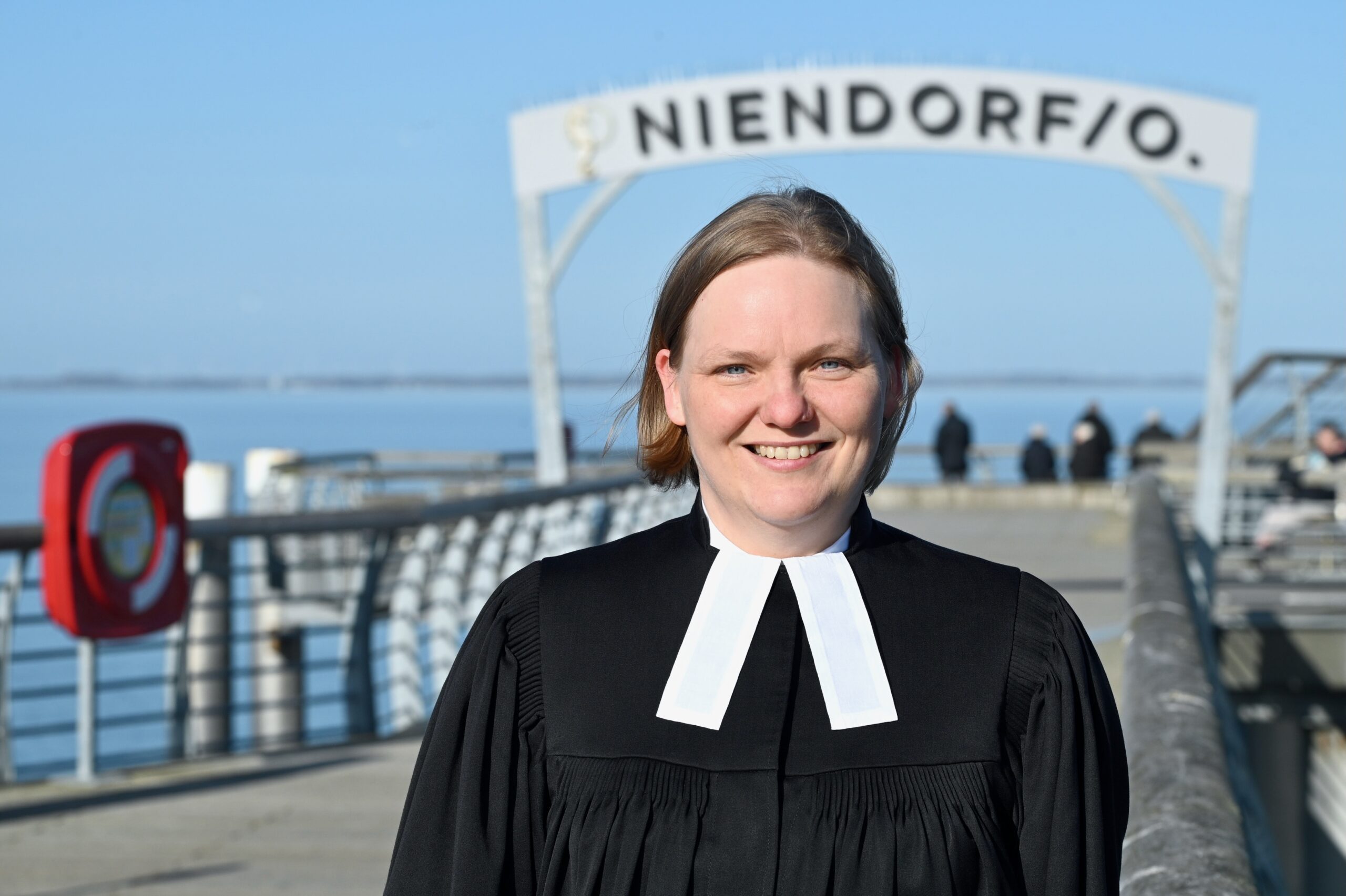 Pastorin im schwarzen Talar auf der Seebrücke Niendorf.